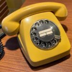 Kollane retro telefon laua peal.