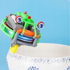 Roheline kahe silma ja ühe rattaga robot, mis sõidab mööda vaasi serva.