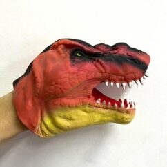 Kummist valgete hammastega oranž käpiknukk dino käes.