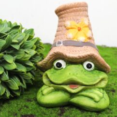 Roheline keraamiline konn mütsiga põõsa kõrval.