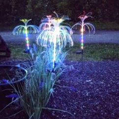 Päikeseenergial töötavad värviliste tuledega meduusikujulised lambid kivikattega pinnasel.