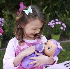 Väike tüdruk koos libliknukuga aias.