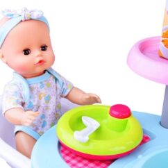 Nukk kes istub oma beebitoolis.Tema ees on roheline taldrik ja lusikas.