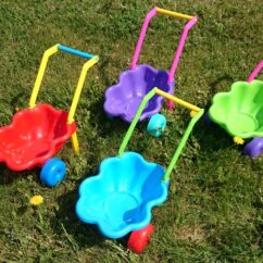 Värvilised laste aiakärud merikarbi kujuga muruplatsil.