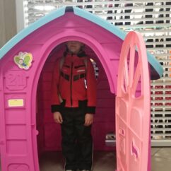Roosa mängumaja, mille sees seisab laps.