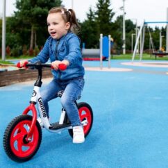 Laps sõidab mänguväljakul jooksuratas gimmega.