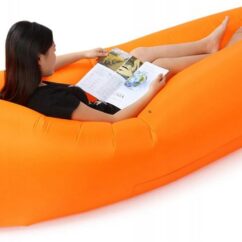 Oranž täispuhutud lebodiivan milles inimene istub ja loeb raamatut.