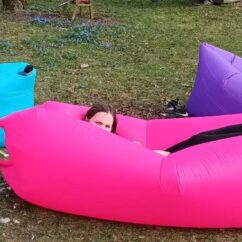 Täispuhutud lebodiivanid roosa, sinine ja lilla muruplatsil, millel pikutavad lapsed.