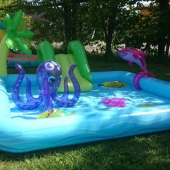 Täispuhutav sinine veemänguväljak mereloomadega muruplatsil.