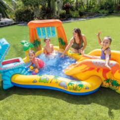 Laste kollane täispuhutav veemänguväljak krokodilli, pallide ja dinosauruse teemaga, koos lastega muruplatsil.