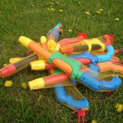 Värvilised veepüstolid hunnikus muruplatsil.